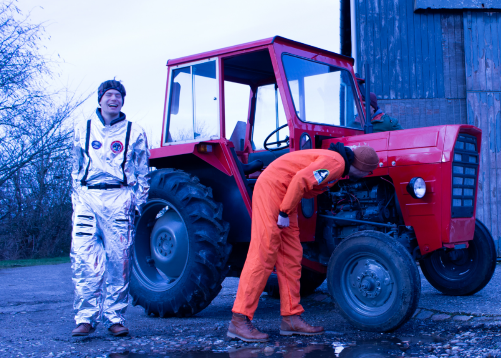 Mænd i rumdragter, der kigger på en rød traktor i retro-stil.